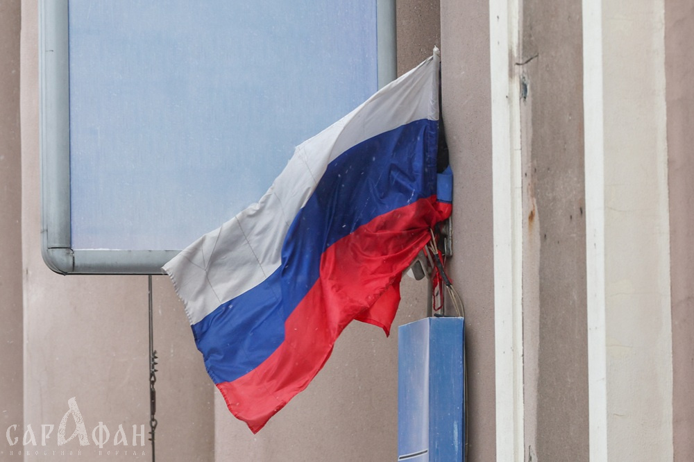 В Краснодаре неизвестная женщина срывает российские флаги и выбрасывает их в мусорку